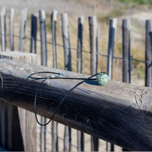 collier en jaspe à taches vertes posé sur du bois