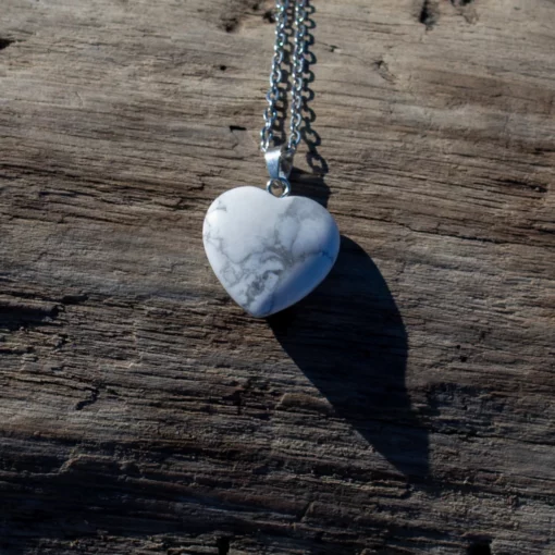 collier cœur en howlite, posé sur un bois flotté