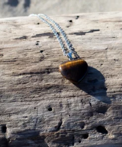 collier cœur en œil de tigre, posé sur bois flotté