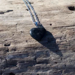 collier cœur en onyx, posé sur bois flotté