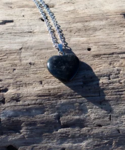 collier cœur en onyx, posé sur bois flotté