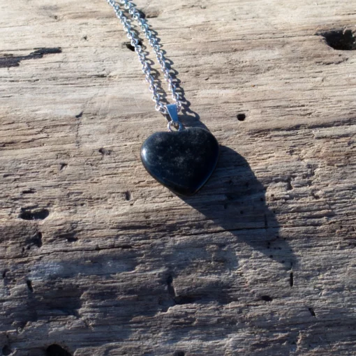 collier cœur en onyx, posé sur bois flotté