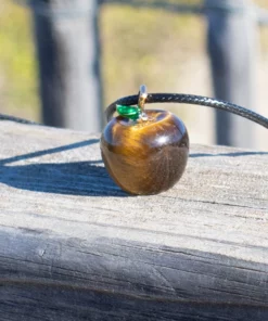 zoom sur le collier pommes d'amour en oeil de tigre posé sur du bois