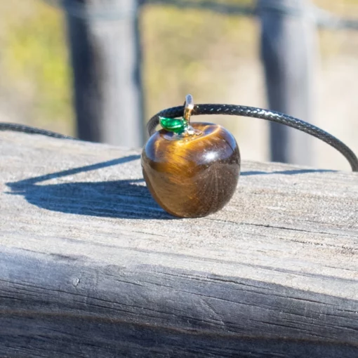 zoom sur le collier pommes d'amour en oeil de tigre posé sur du bois