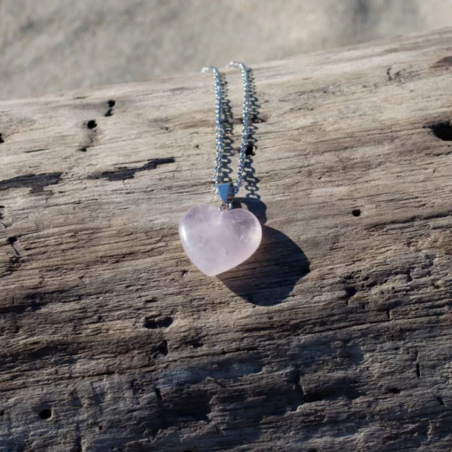 collier en quartz rose, posé sur du bois flotté