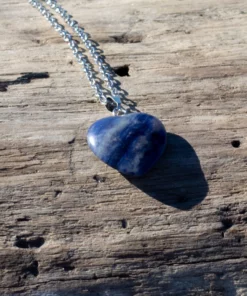 collier cœur en sodalite posé sur un bois flotté