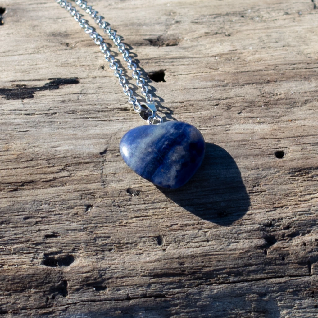 collier cœur en sodalite posé sur un bois flotté